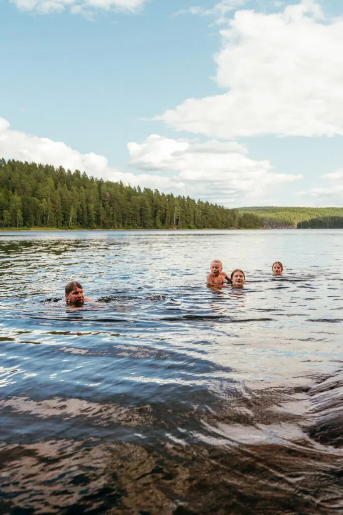 family swimming in a lake surrounded by forest