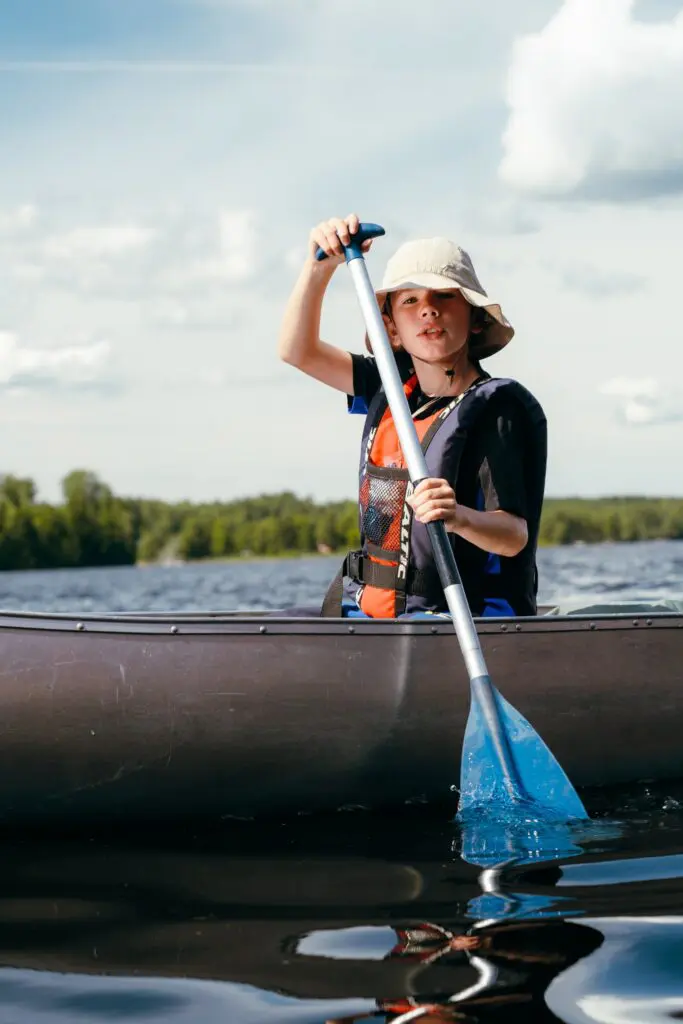 child in a canoe paddling on a lake