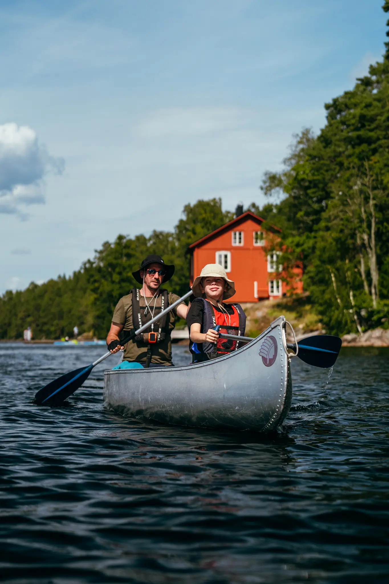 two people canoeing on a lake with a red house in the background