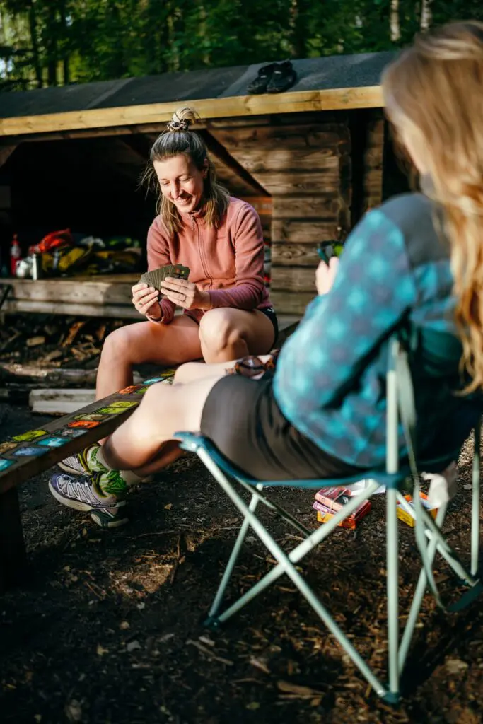 two women playing cards outside a wooden cabin