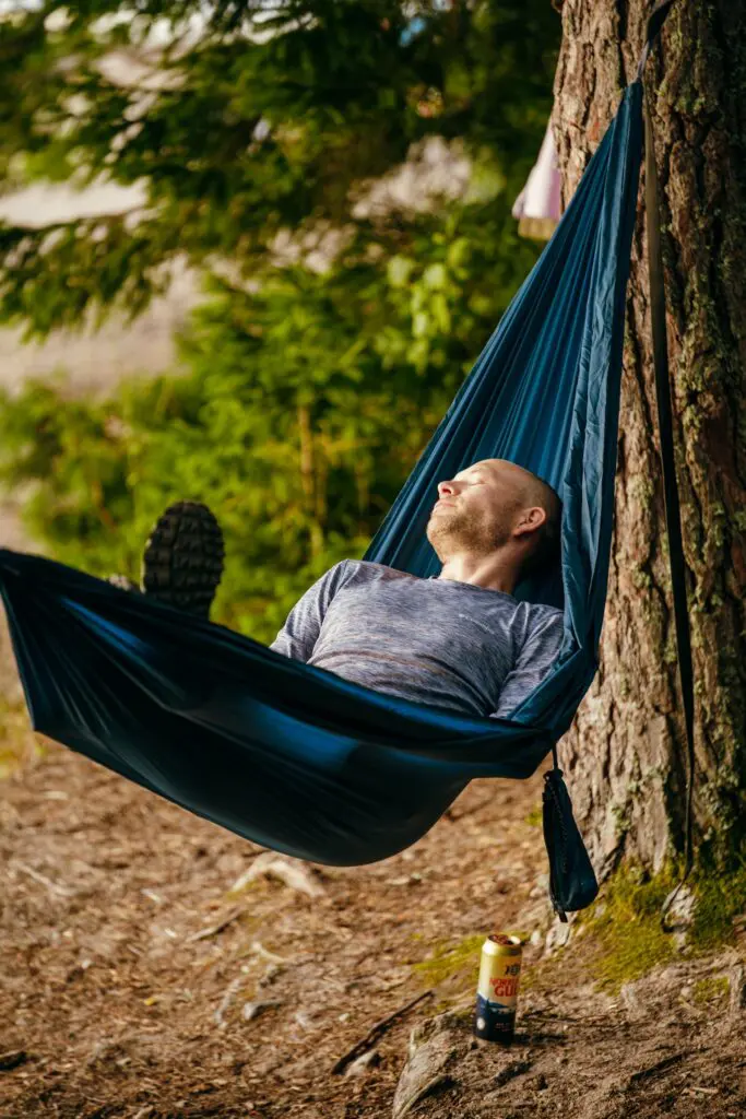 man relaxing in a hammock outdoors with a drink