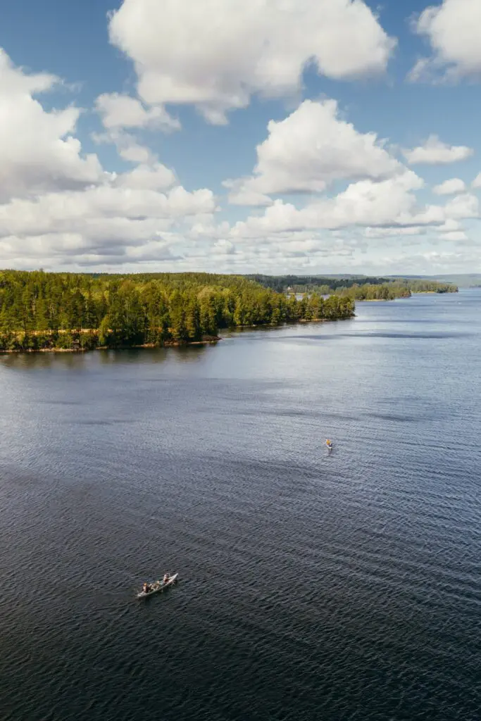 aerial view of a lake with canoes and forested shore