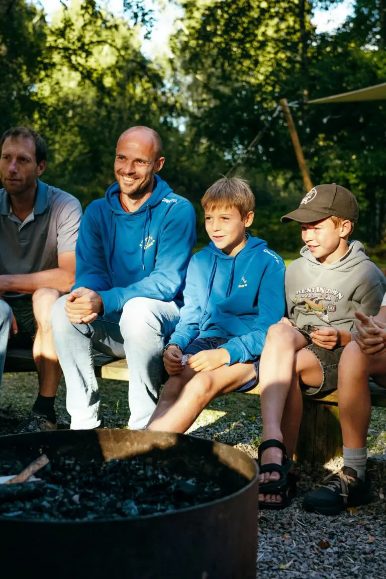 group of men and boys sitting around a campfire