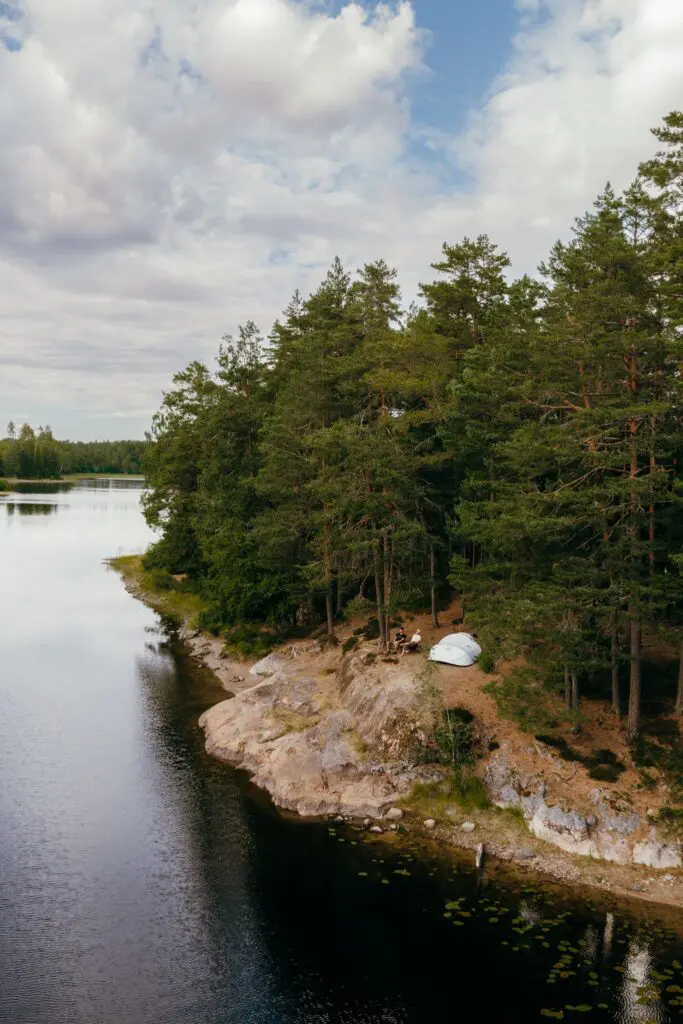 drone shot of two people camping by a lake in a forest