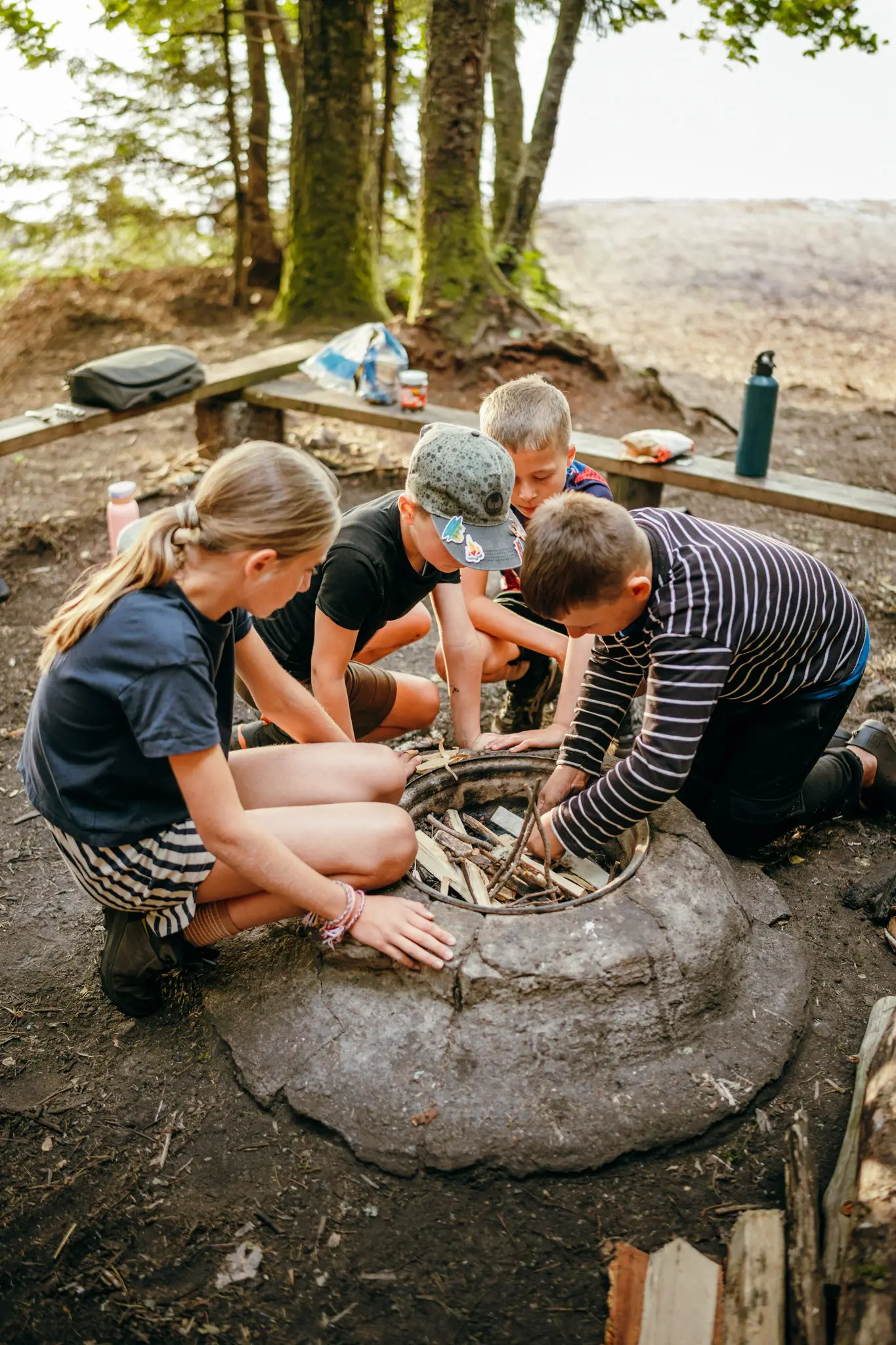 four children preparing a campfire in a forest