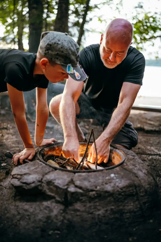 father and son starting a campfire outdoors