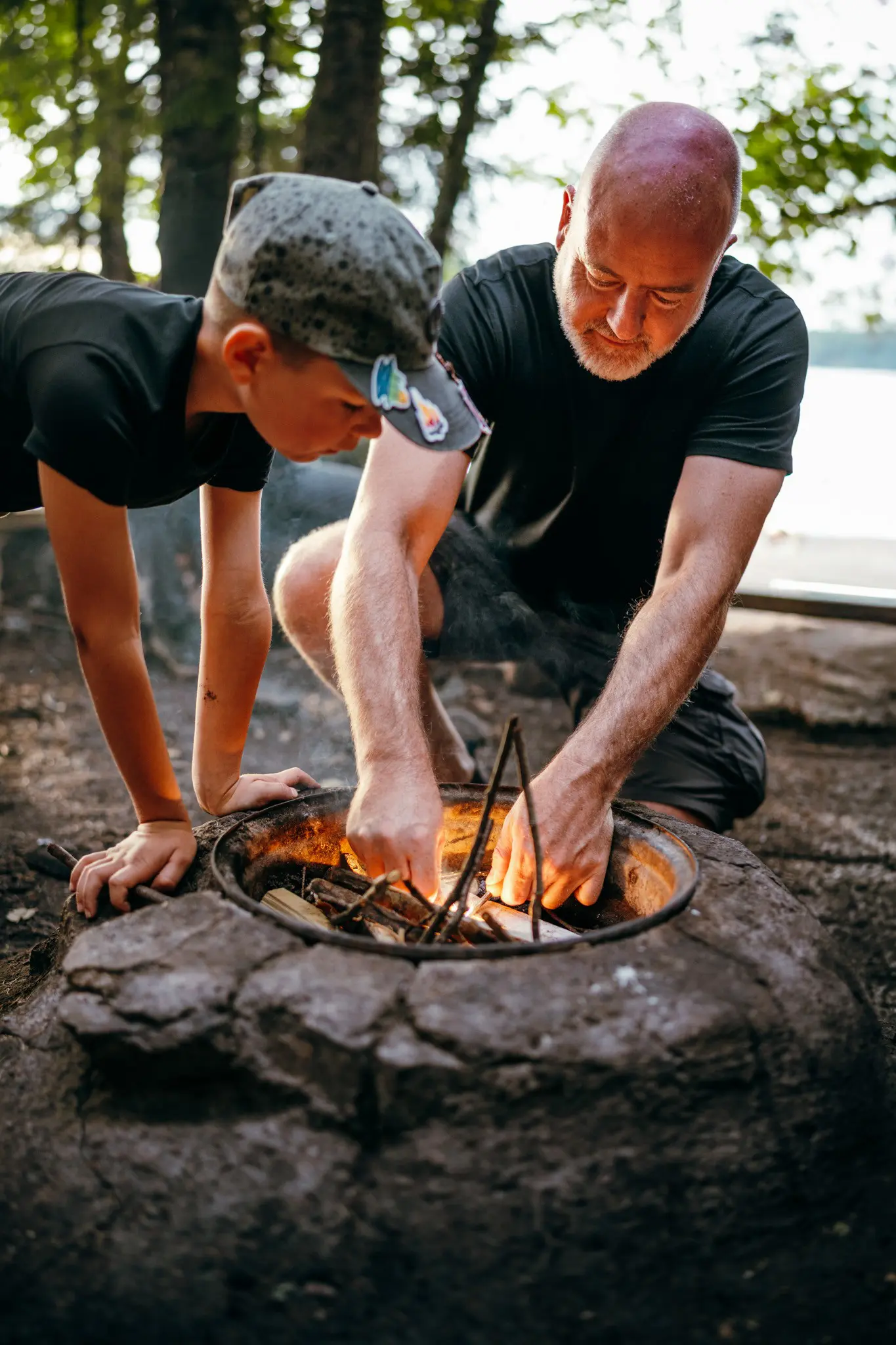 father and son starting a campfire outdoors