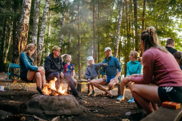 group of people sitting around a campfire in a forest