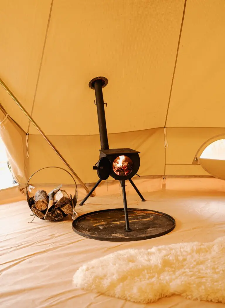 wood burning stove inside a glamping tent with firewood