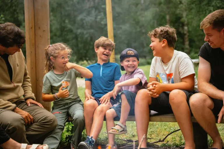 group of children and adults laughing around a campfire