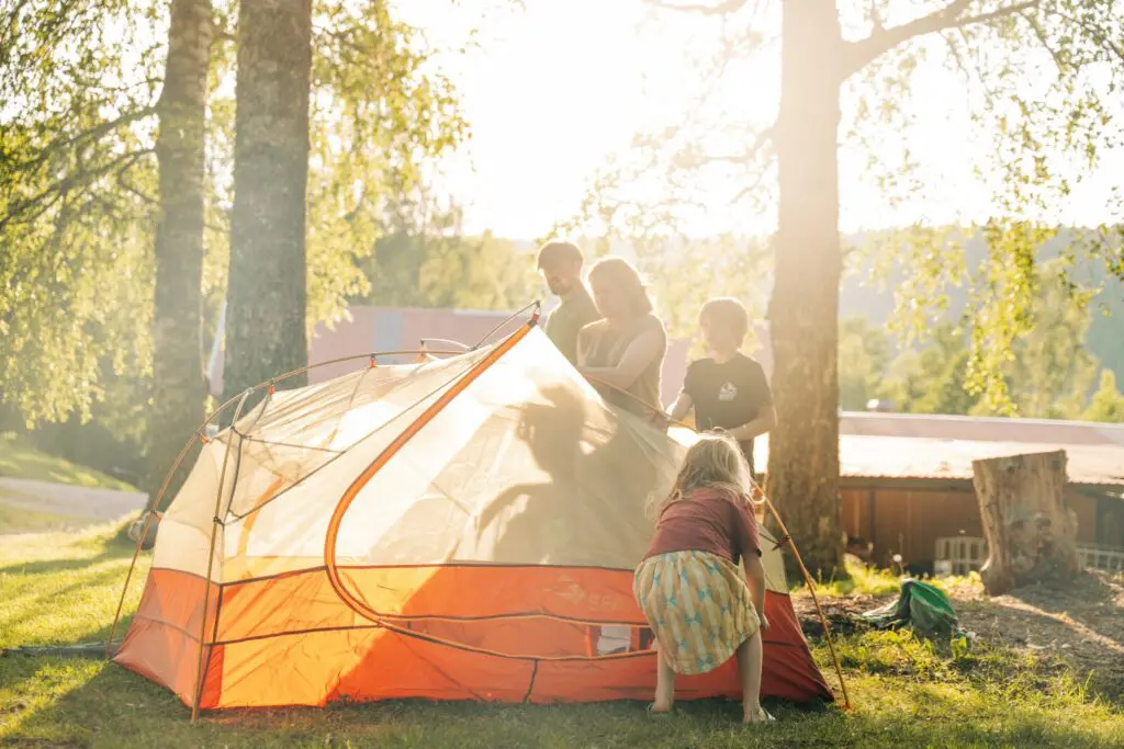 family setting up a tent in a sunny campsite