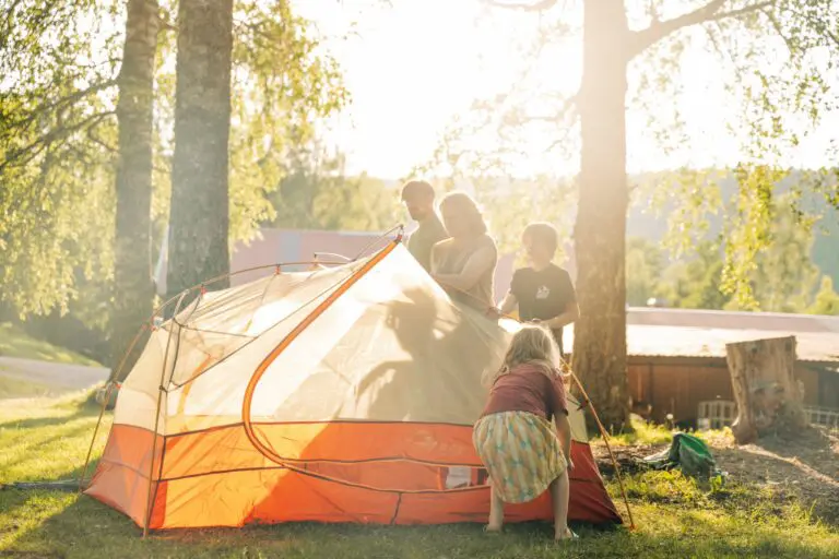 family setting up a tent in a sunny campsite
