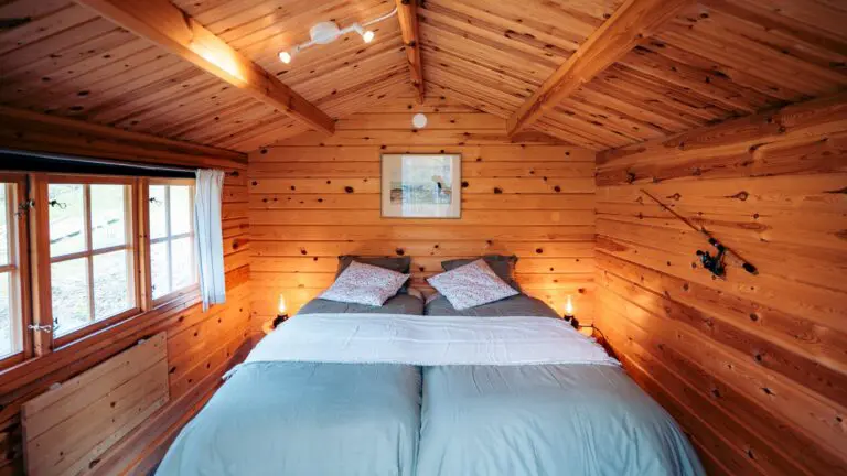 cozy wooden cabin interior with twin beds and fishing rod