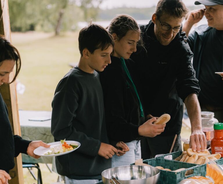 group of people serving themselves food outdoors